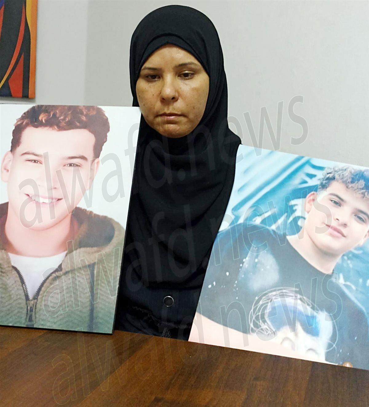 والدة الضحية تحتضن صور إبنها