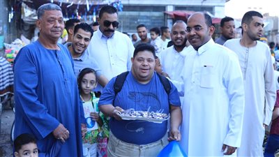 شاب قبطى من ذوى الهمم يوزع الحلوى على المصلين احتفالًا بعيد الفطر 