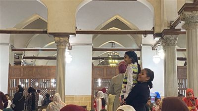 طفلة تحمل شقيقتها الصغيرة على كتفها لرؤية صلاة العيد في جامع الأزهر