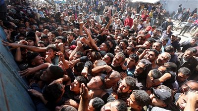 فلسطينيون يتجمعون للحصول على الخبز في دير البلح.. صور