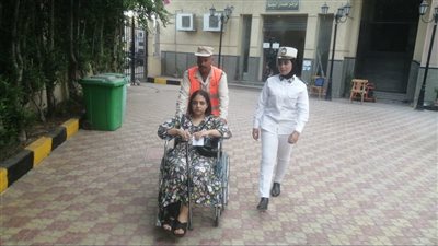 الشرطة النسائية بالبحيرة تساعد فتاة تجلس على كرسي متحرك للإدلاء بصوتها بانتخابات الشيوخ