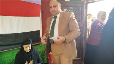 رئيس لجنة سيلا الابتدائية بالفيوم يساعد سيدة مسنّة في الإدلاء بصوتها 