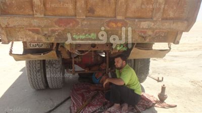 ظلال اللوادر والشاحنات مضاجع العمال في ساعات الراحة
